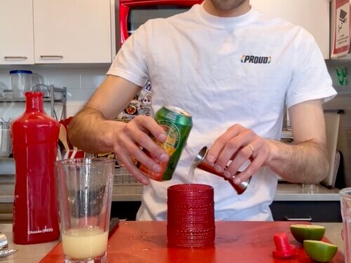 Man pours ginger beer into cocktail glass