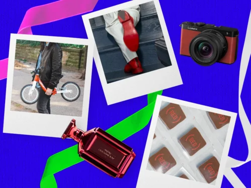 A collage of (RED) products on a festive blue background with purple and green ribbons. Some products are featured as instant-photo printouts. The products included are: the (WOOM)ᴿᴱᴰ Original bike, (SAVAS)ᴿᴱᴰ Legend Boot, (AROMA360)ᴿᴱᴰ Red Parfum, (PANASONIC)ᴿᴱᴰ Lumix S9, and (KREUTHER HANDCRAFTED CHOCOLATE)ᴿᴱᴰ Signature Chef’s Selection